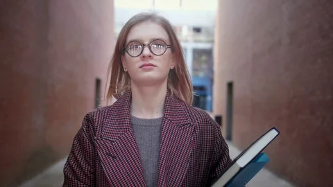 Beautiful young smart trendy nerd or geek girl in glasses walking towards Stock Footage 104788888