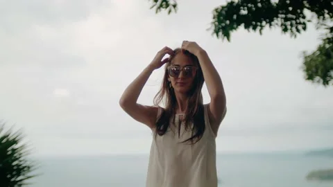 A beautiful young smiling long-haired girl in sunglasses looks at the camera and Video stock 130282985