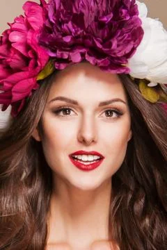 Beautiful young smiling model with bright flowers on her head Stock Photos