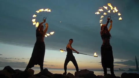 A beautiful young team makes a fire show against the backdrop of the sunset sky 库存影片 194372254