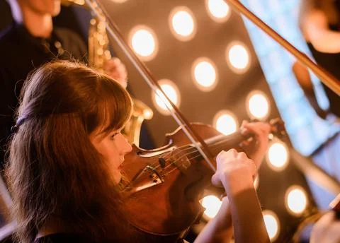 Beautiful young violinist on the background of a string orchestra Stock-Fotos