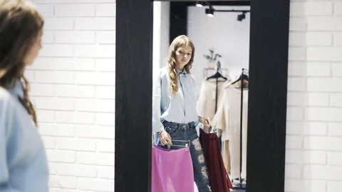 Beautiful young woman choosing clothes in shop Stock Footage
