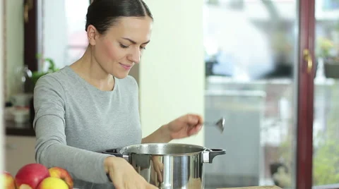 Beautiful young woman cooking and testing the food in the kitchen HD Stock Footage