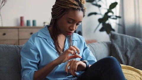 Beautiful young woman with dreadlocks, in casual wear uses the smart watch while Stock Footage