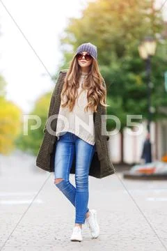 Beautiful young woman in green knitted cardigan with a hood walking in autumn Stock Photos