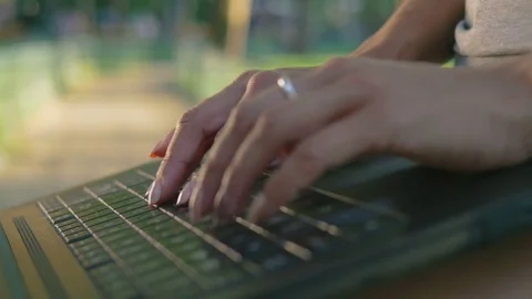 Beautiful young woman in hat using laptop in park, close up shot Stock Footage