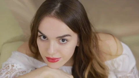 Beautiful young woman at home. looking at camera with arm leaning on the sofa Stock Footage