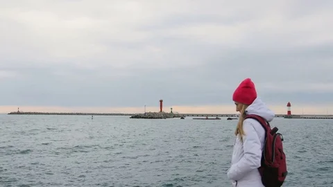 Beautiful young woman in jacket with backpack walk on pier at harbor. Attractive Video stock 71631925