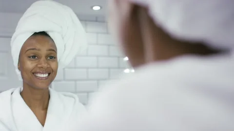 Beautiful young woman moisturising her face in the mirror Vidéo gratuite 57175083