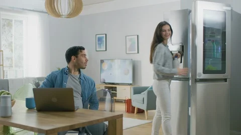 Beautiful Young Woman Opens the Fridge and Gives a Milk Bottle to Her Boyfriend. Stock Footage