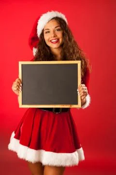 Beautiful young woman in santa dres holds blackboard over red background Stock Photos