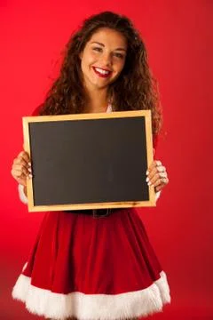 Beautiful young woman in santa dres holds blackboard over red background Stock Photos