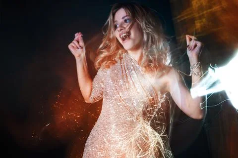 Beautiful young woman in a shiny dress dancing in a nightclub, Stock Photos