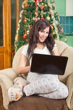 Beautiful young woman sitting on sofa with laptop computer smiling Stock Photos