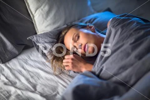 Beautiful young woman sleeping in bed (colour toned image; shallow DOF) Stock Photos