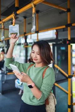 Beautiful young woman standing in city bus and talking on mobile phone. Stock Photos