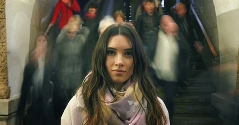Beautiful young woman standing in moving crowd in subway, looking at camera Stock Footage