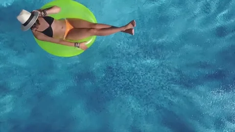 Beautiful young woman in swimming pool on inflatable ring, aerial view Stock Footage