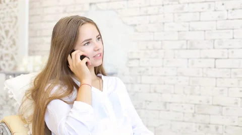 Beautiful young woman talking on mobile phone at home Stock Footage