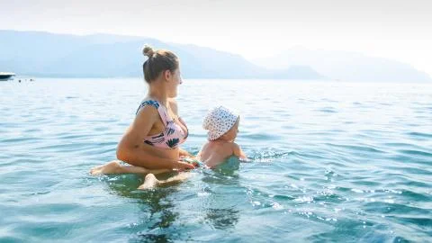 Beautiful young woman teaching her little child swimming in th elake Stock Photos