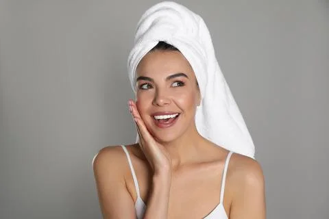 Beautiful young woman with towel on head against grey background Stock Photos