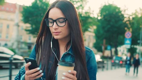 Beautiful young woman using smart phone, typing messages, listening to music Stock Footage 76128808