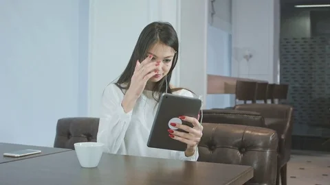 Beautiful young woman using a tablet pc to make a video call while sitting in a Vídeos de archivo 72017519