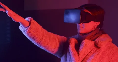 Beautiful young woman using virtual reality glasses on neon lighting background Stock Footage 119499747