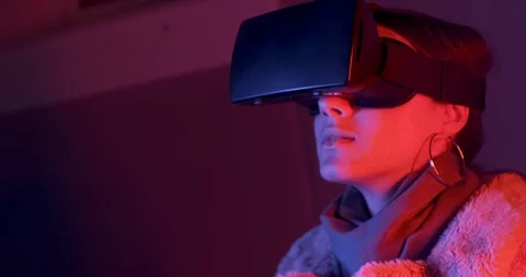 Beautiful young woman using virtual reality glasses on neon lighting background Видео 119499948