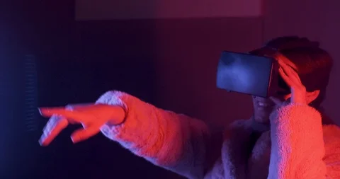 Beautiful young woman using virtual reality glasses on neon lighting background 스톡 동영상 119776858