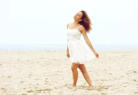 Beautiful young woman walking on beach in white dress Foto stock