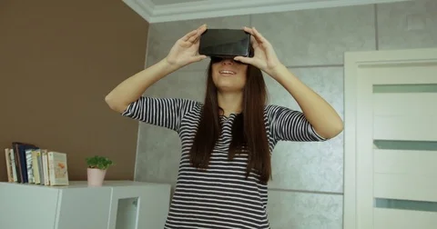 Beautiful young woman wearing VR headset looking at the virtual objects and Stock Footage