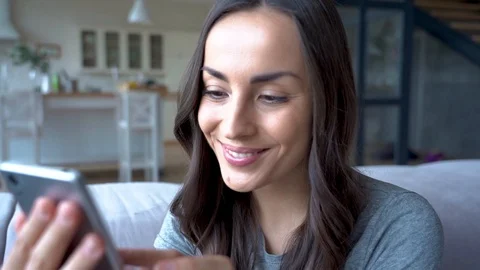 Beautiful young woman while she using mobile phone and sitting on the couch Stock Footage 108611005