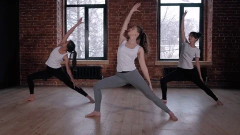 Beautiful young yoga instructor smiling and group of students during one of her Stock Footage 72290244