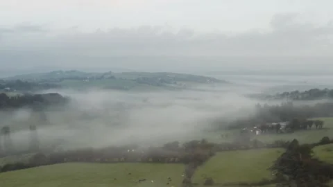 BEAUTIFULL AERIAL SHOT OF A FOGGY MORNING ON GREEN FIELDS Stock Footage