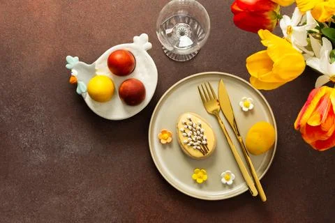 A beautifully arranged Easter table displays vibrant eggs, elegant gold cut.. Stock Photos