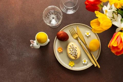 A beautifully arranged Easter table displays vibrant eggs, elegant gold cutle Stock Photos