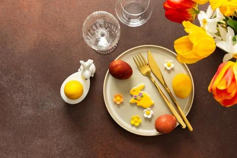 A beautifully arranged Easter table displays vibrant eggs, elegant gold cutle Stock Photos