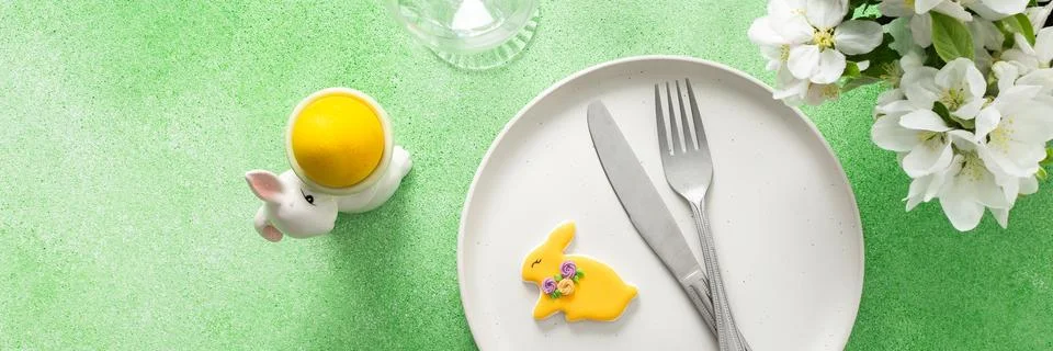A beautifully arranged Easter table features a plate with a yellow bunny cook Stock Photos