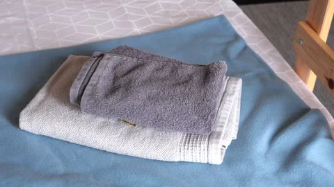 A beautifully arranged stack of towels on a soft blue surface, creating a Stock Footage 280814541