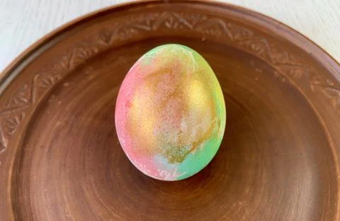 A beautifully decorated Easter egg sits on a rustic wooden plate. The egg Foto stock