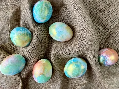 Beautifully decorated Easter eggs in vibrant colors are scattered across a soft 스톡 사진