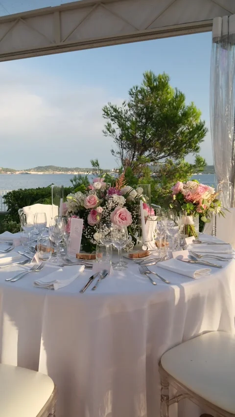 Beautifully decorated round table with a white tablecloth, pink rose bouquets Stock Footage 344007396