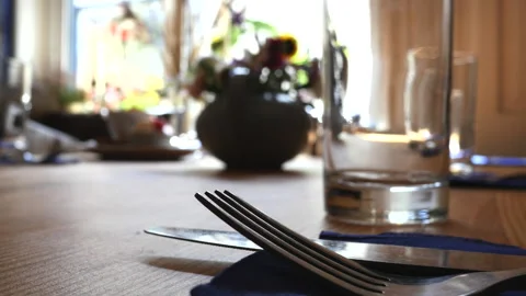 A beautifully set dining table with a fork and knife in sharp focus, surrounded Stock Footage 301384067