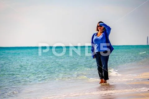 Beautiiful woman walking on a sunny white sand beach 1047-84 Stock Photos