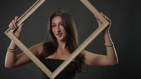 Beauty and self-perception concept, young woman holding empty frame around her Stock Footage 336936791