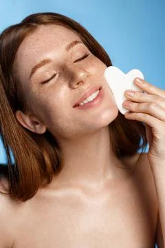 Beauty and skincare. Smiling sensual redhead girl massage facial skin, facelift Stock Photos