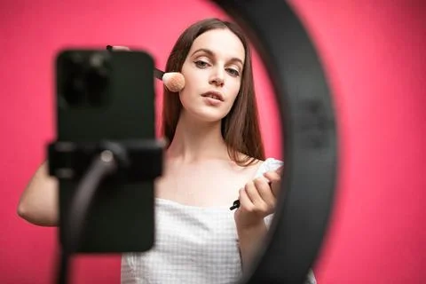 Beauty blogger recording makeup tutorial on pink background Stock Photos