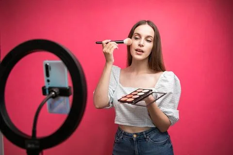 Beauty blogger recording makeup tutorial on pink background Stock Photos