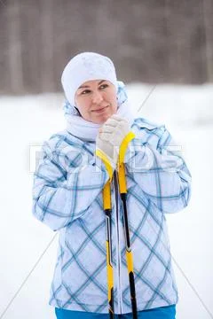 Beauty caucasian woman warming frozen hands with ski poles in winter Stock Photos
